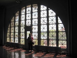 I'm standing in front of the large arched window at the Ellis Island Immigration Museum