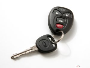 A car key dangles from a fob with controls on it.