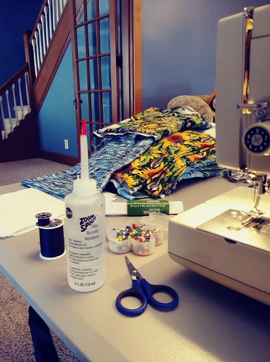 A plastic bottle of sewing oil surrounded by sewing paraphernalia: thread, pins, fabric, elastic, and scissors.